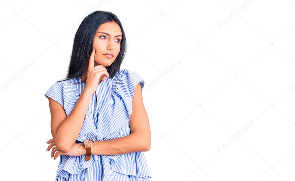 Young beautiful latin girl wearing casual clothes with hand on chin thinking about question, pensive expression. smiling with thoughtful face. doubt concept. 