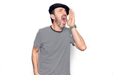 Orta yaşlı yakışıklı bir adam beyaz arka planda çizgili tişört ve Fransız beresi giyiyor ve el ele tutuşarak bağırıyor. İletişim konsepti.