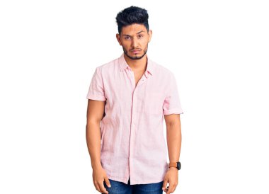 Yakışıklı Latin Amerikalı genç adam gündelik yaz gömleği giyiyor şüpheci ve gergin, sorun yüzünden surat asıyor. negatif kişi. 