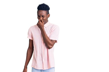 Genç, Afro-Amerikan bir adam günlük giysiler giymiş pis ve iğrenç bir koku alıyor, dayanılmaz bir koku, parmakları burnunda nefesini tutuyor. Kötü kokuyor. 