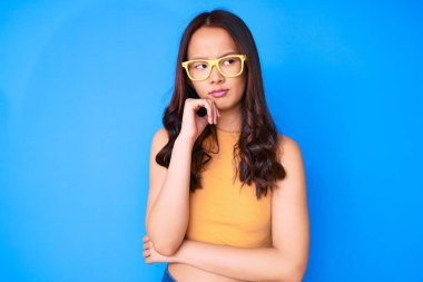 Genç, güzel Çinli bir kız, günlük kıyafetler ve gözlük takıyor ciddi bir yüz, eli çenesinde soruyu düşünüyor, kafa karıştırıcı bir fikir. 