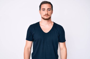 Yüzünde ciddi bir ifade olan sıradan kıyafetler giyen genç yakışıklı bir adam. Basit ve doğal bir şekilde kameraya bakıyorsun.. 