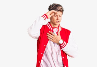 Beyzbol üniforması giyen yakışıklı genç adam hastalık ve ateş için alnına dokunuyor, grip ve soğuk algınlığı, virüs. 