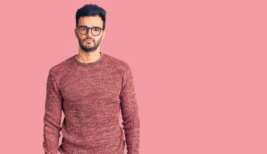 Kışlık süveter giyen, gözlüklü, kuşkucu ve sinirli genç, sorun yüzünden üzgün. negatif kişi. 