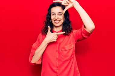 Gündelik giysiler giymiş, gülümseyen, elleri ve parmakları gülen yüzlü, güzel İspanyol bir kadın. yaratıcılık ve fotoğrafçılık kavramı. 