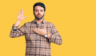 Latin asıllı genç adam, gündelik giysiler giyip, el pençe divan yemin ederek sadakat yemini ediyor. 