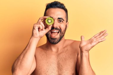 İspanyol asıllı genç adam elinde kivi tutarak başarıyı mutlu bir gülümsemeyle kutluyor ve kazanan el kaldırıyor. 