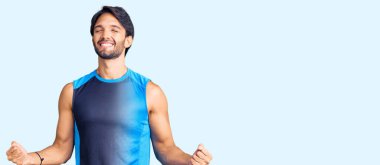 Spor kıyafetleri giyen yakışıklı İspanyol adam kolları havada ve gözleri kapalı zaferi kutlarken heyecanla bekliyor. Kazanan konsept. 