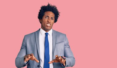 Afro saçlı, iş ceketi giyen yakışıklı Afro-Amerikalı adam tiksindirici ve tiksindirici bir yüz ifadesi takınıyor.. 