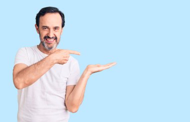 Sıradan tişörtler giyen orta yaşlı yakışıklı adam kameraya hayret ediyor ve gülümsüyor.. 