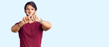 Yakışıklı İspanyol bir adam günlük kıyafetleri giyiyor. Reddedilme yüz ifadesi. Eksi işareti yapıyor. 