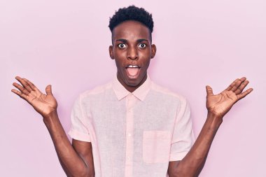 Genç Afro-Amerikan adam gündelik giysiler giyip zaferi mutlu bir gülümsemeyle ve ellerini kaldırarak kutluyor. 