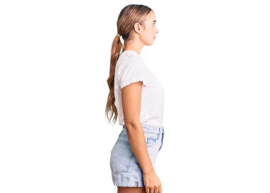 Genç, güzel, sarışın bir kadın, günlük beyaz tişört giyiyor. Yan tarafa bakıyor, rahat bir poz veriyor, kendine güvenen bir gülümsemeyle doğal bir yüz takınıyor.. 