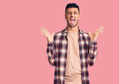 Gündelik kıyafetler giyen genç İspanyol adam başarı için deli ve çılgınlığı kutluyor kollarını kaldırmış ve gözlerini kapatmış heyecanla bağırıyor. Kazanan konsept 