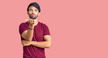 Yakışıklı, sıradan kıyafetler giyen, kameraya bakıp havada el sallayan yakışıklı, güzel ve seksi bir adam. aşk ifadesi. 