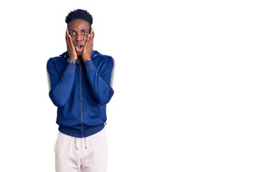 Afro-Amerikalı genç adam spor kıyafetleri giyiyor. Korkmuş ve şok olmuş. Şaşırmış ve şaşırmış bir halde. 