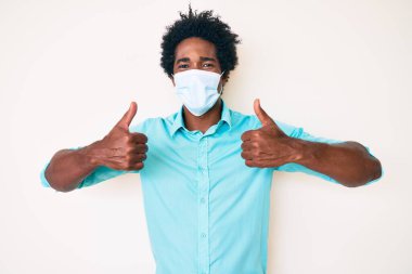 Yüzünde mutlu ve havalı bir gülümsemeyle gülümseyen Afro saçlı yakışıklı Amerikalı bir adam. diş gösterme. 