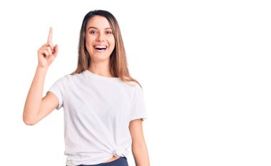 Gündelik tişört giyen genç ve güzel bir kız başarılı bir fikri işaret ediyor. Heyecanlı ve mutlu. Bir numara.. 