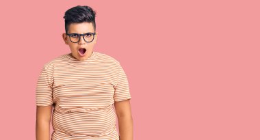 Günlük giysiler ve gözlük takan küçük çocuk şaşkınlık ve şaşkınlık dolu bir ifade, korku ve heyecanlı bir yüz ifadesiyle şoka uğradı.. 