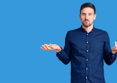 Gündelik tişört giyen genç, yakışıklı ve kolları açık, hiçbir fikri olmayan biri.. 