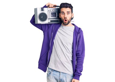 Sakallı genç yakışıklı adam klasik teyp kullanarak müzik dinliyor korkmuş ve ağzı açık bir şekilde şaşırmış, inançsız bir yüz. 