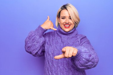 Güzel sarışın ve cüsseli bir kadın mor arka plan üzerine balıkçı yaka kazak giyiyor gülümsüyor telefonda konuşuyor ve seni işaret ediyor. Ara beni..