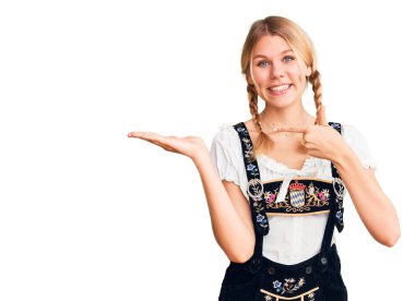 Oktoberfest elbisesi giyen genç ve güzel sarışın kadın kameraya hayret ediyor ve gülümsüyor.. 