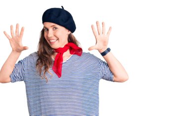 Fransız beresi ve çizgili tişört giyen genç ve güzel sarışın kadın on numaralı parmaklarını gösterirken kendinden emin ve mutlu bir şekilde gülümsüyor.. 