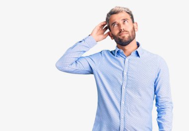 Zarif tişört giyen yakışıklı sarışın genç adam soru sorup kafasını karıştırıyor. Şüpheyle kararsız, kafa kafaya düşünerek. Düşünceli kavram. 