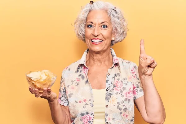 Kıdemli Gri Saçlı Kadın Elinde Patates Cipsi Bir Fikirle Gülümsüyor — Stok fotoğraf