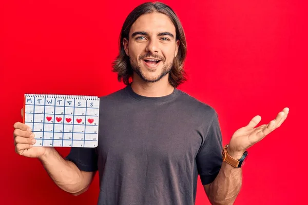 Joven Hombre Guapo Sosteniendo Calendario Del Corazón Celebrando Logro Con — Foto de Stock