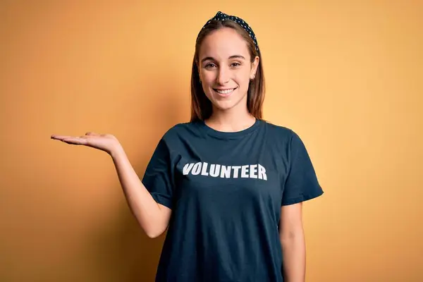 Młoda Piękna Kobieta Ochotniczej Koszulce Robi Wolontariat Nad Żółtym Tłem — Zdjęcie stockowe