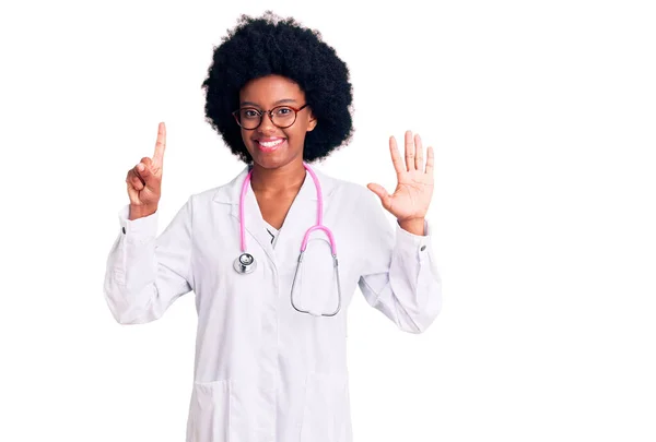 若いですアフリカ系アメリカ人女性を身に着けています医師のコートと聴診器を表示し 指番号6で指摘しながら 自信と幸せ — ストック写真