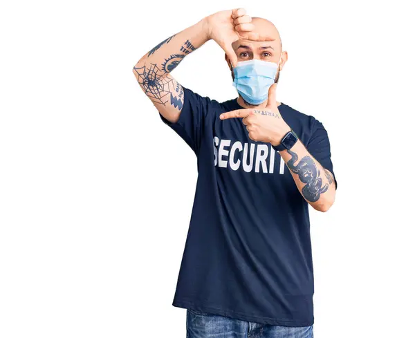 セキュリティTシャツを着た若いハンサムな男と幸せな顔で手や指でフレームを作る笑顔医療用マスク 創造性と写真の概念 — ストック写真