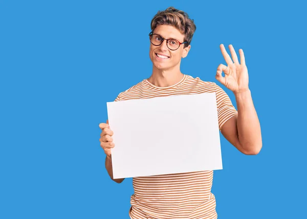 Joven Hombre Guapo Sosteniendo Pancarta Vacía Blanco Haciendo Signo Bien —  Fotos de Stock