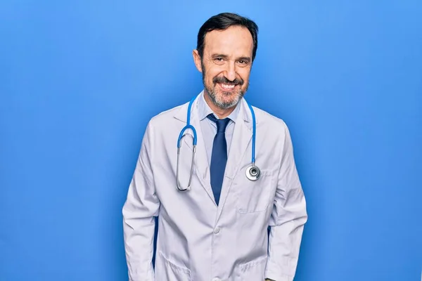中年男子 英俊的医生 身穿外套和听诊器 带着淡淡的蓝色背景 脸上挂着快乐而沉着的微笑 幸运的人 — 图库照片