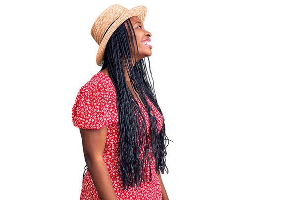 Young african american woman wearing summer hat looking away to side with smile on face, natural expression. laughing confident.