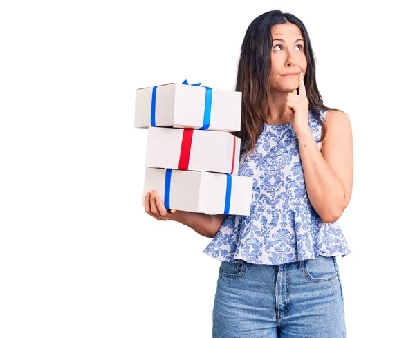 Young Beautiful Brunette Woman Holding Birthday Gift Serious Face Thinking — Stock Photo, Image