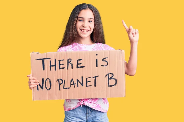 かわいいヒスパニック系の子供の女の子が幸せな顔で指を指してアイデアや質問に驚いていない惑星Bのバナーが保持し ナンバーワン — ストック写真
