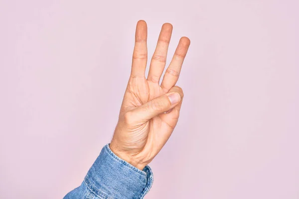 孤立したピンクの背景の上に指を示す白人青年の手数3指を示しています — ストック写真