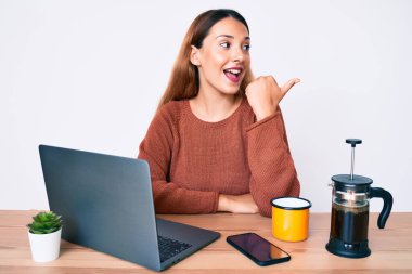 Genç esmer kadın ofiste çalışıyor. Bir fincan kahve içiyor. Başparmağını kaldırıp gülümsüyor. 