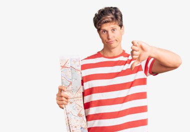 Şehir haritası tutan genç yakışıklı bir adam, kızgın yüzlü, negatif işaretli baş parmakları aşağıda, reddedilme konsepti. 