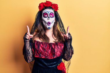 Ölü kostümünü giydiği gün şaşırmış ve şaşırmış genç bir kadın yukarı baktı ve parmaklarıyla işaret etti ve kolunu kaldırdı.. 