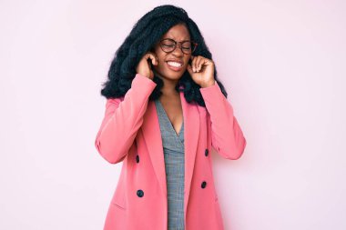 Güzel bir Afrikalı kadın iş ceketi giyiyor ve yüksek sesli müzik sesi için kulaklarını parmaklarıyla kapatıyor. sağır kavramı. 