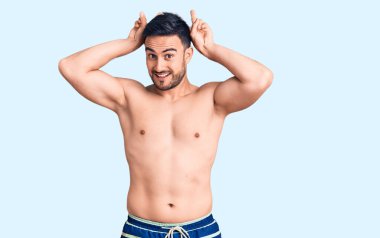 Mayo giyen genç yakışıklı komik ve çılgın poz veren parmakları tavşan kulaklı, neşeli gülümseyen 