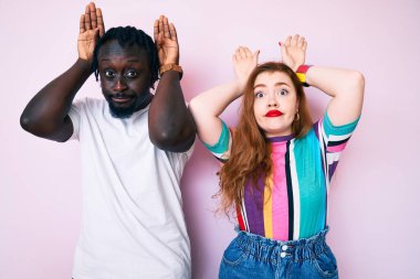 Irklar arası çiftler günlük kıyafetler giyip tavşan kulağı yapıyorlar. Avuçlarıyla alaycı ve şüpheci görünüyorlar. Paskalya tavşanı konsepti. 