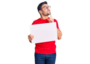 Genç İspanyol asıllı boş pankart tutan, ciddi bir yüz ifadesi olan, eli çenesinde soru soran, kafa karıştırıcı bir fikir hakkında düşünceli genç adam. 