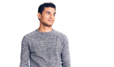 İspanyol asıllı yakışıklı, sıradan bir süveter giyen, gülümseyen, yan bakan ve düşünen genç bir adam.. 