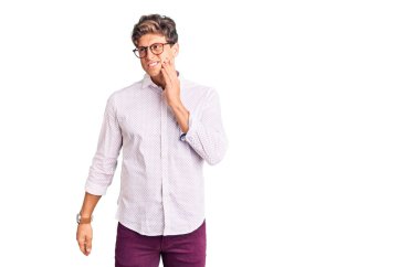 İş elbiseleri ve gözlük takan genç yakışıklı bir adam diş ağrısı ya da diş hastalığından dolayı acı dolu bir ifadeyle ağıza dokunuyor. dişçi 