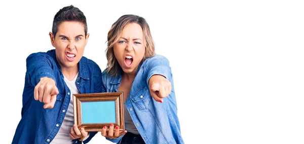 Couple Women Holding Empty Frame Pointing Displeased Frustrated Camera Angry — Stock Photo, Image